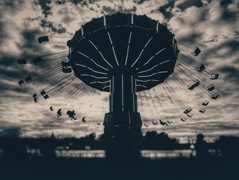 Low angle view of chain swing ride against cloudy sky