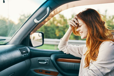 Side view of woman sitting in car