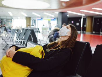 Midsection of woman using mobile phone while sitting on chair