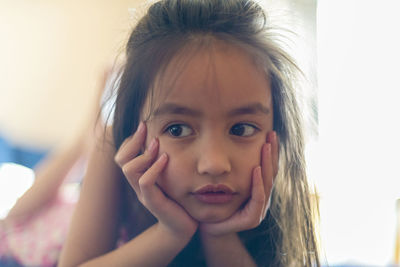 Close-up of thoughtful girl leaning on elbows at home