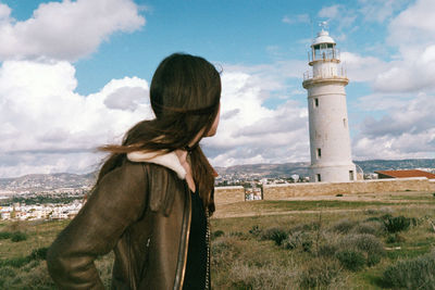 View of woman standing by lighthouse against sky