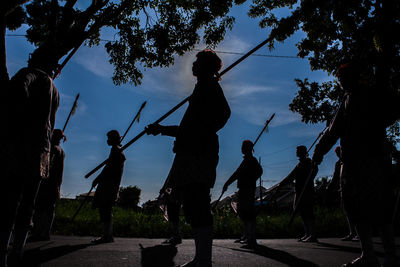 Silhouette man standing by trees against sky