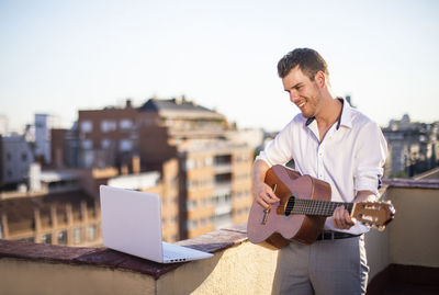 Handsome young singer performing for his fans on social media from the roof of his house during quarantine