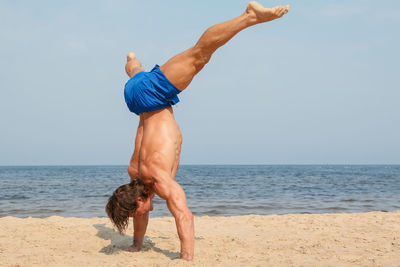 Man practicing handstand at beach