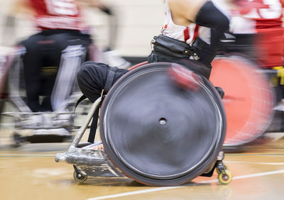 Blurred motion of male athletes playing wheelchair basketball on court