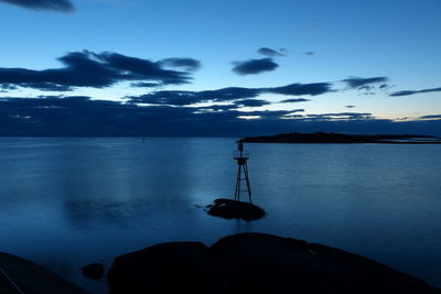 Silhouette rocks by sea against sky at sunset