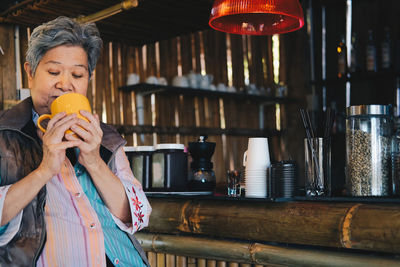 Midsection of woman holding drink at home