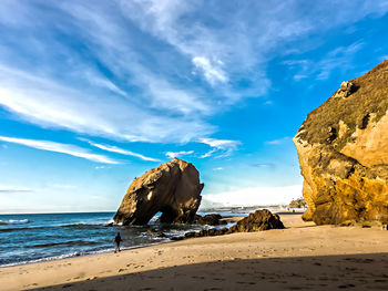 Rock formations on beach against sky