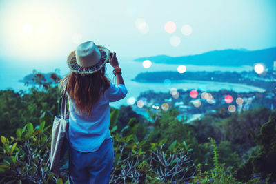 Woman photographing against sky