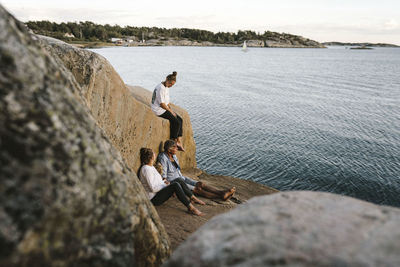 People sitting on rock by sea