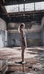 Full length of young woman standing against waterfall