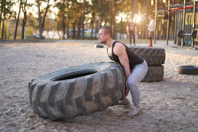 Full length of man exercising with tire on sand