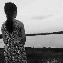 Rear view of girl standing on grassy field against sky