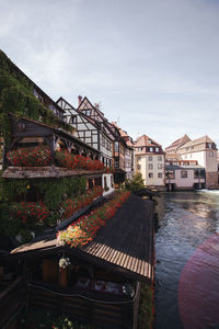 Houses by river and buildings against sky