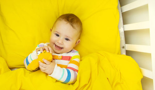 Portrait of cute baby boy lying on bed at home