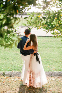 Rear view of couple standing against trees