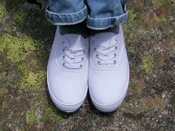 Low section of man wearing white shoes on field