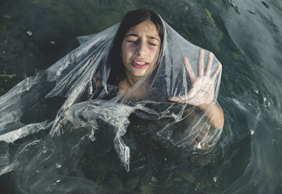 High angle view of girl amidst plastic in sea