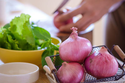 Cropped hand of person cutting onion on kitchen counter at home
