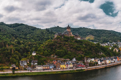 View of building by river against cloudy sky