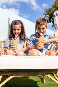 Two cute kids drinking orange juice outdoors