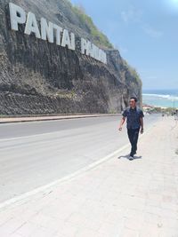 Full length of man standing on footpath against sky