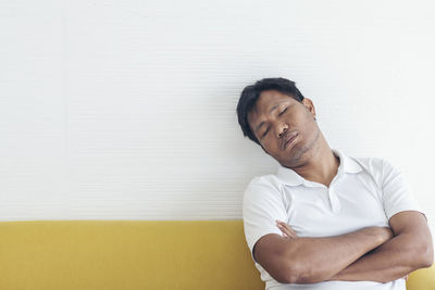 Man looking away while sitting against wall