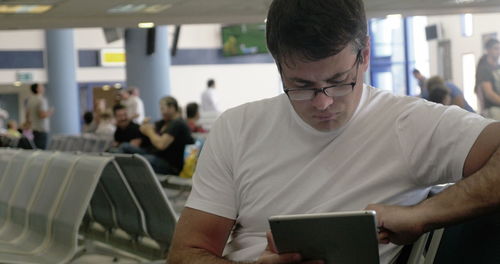 Midsection of man using mobile phone in airport