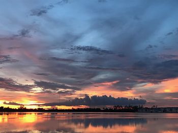 Scenic view of lake against dramatic sky during sunset