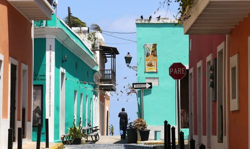 Rear view of man walking on footpath amidst houses