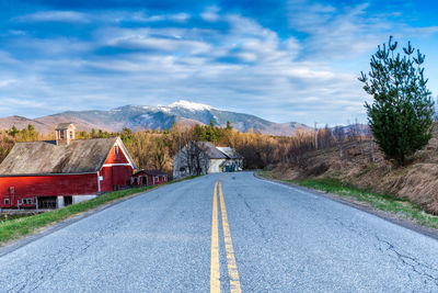 Road by buildings against sky in city