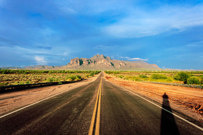 Empty road amidst landscape against sky