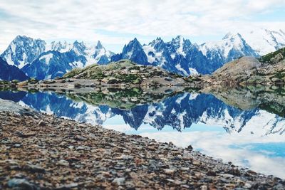 Scenic view of lake by snowcapped mountains against sky