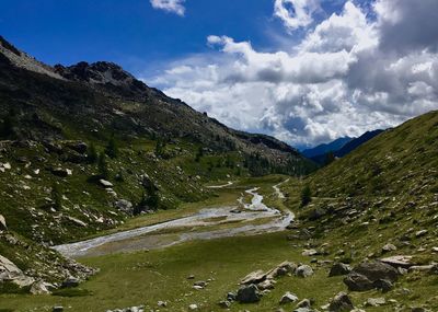 Scenic view of stream amidst mountains against sky