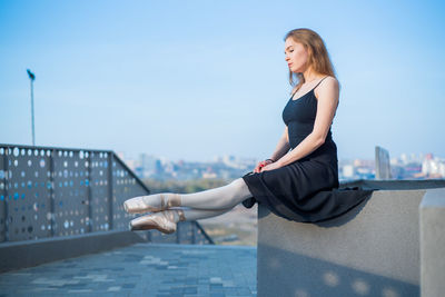 Young woman smiling while standing against railing