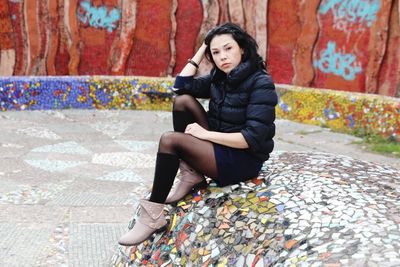 Full length portrait of young woman sitting outdoors