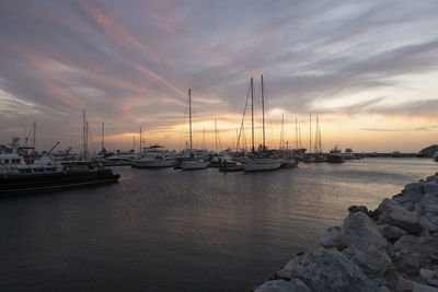 Sailboats moored in marina at sunset