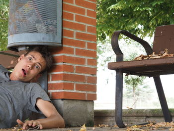 Portrait of surprised man resting under garbage can