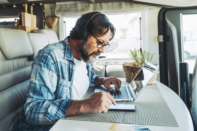 Portrait of senior man using phone while sitting in car