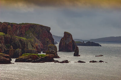 Rocks on sea shore against sky