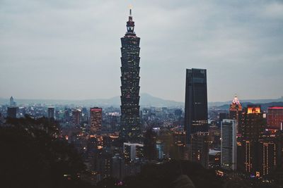 Illuminated cityscape against sky during sunset
