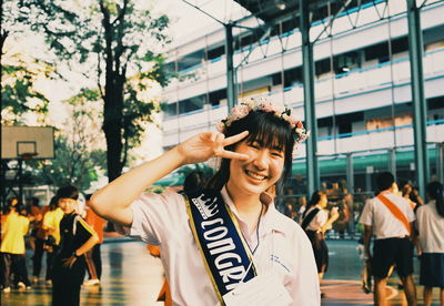 Portrait of smiling young woman standing against people