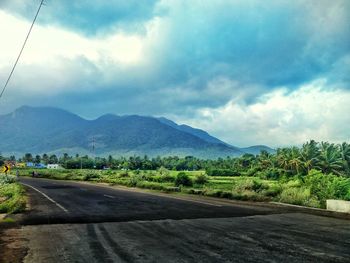 Road by mountains against sky