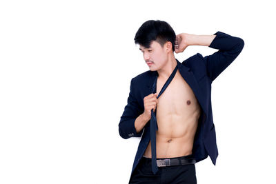 Young man with fully unbuttoned shirt standing against white background