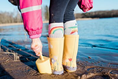 Young child's rain boots and spade on a beach in the sunshine