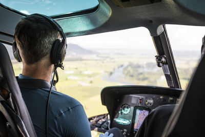 Helicopter pilot flying high above farmland below.