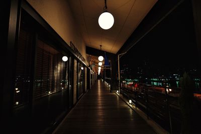 Empty walkway outside cafe in city at night