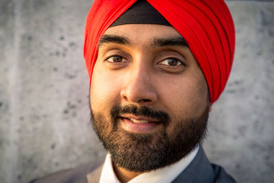 Close-up portrait of businessman wearing turban standing against wall