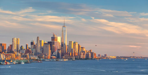 City at waterfront against cloudy sky