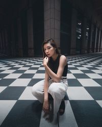 Portrait of young woman sitting on tiled floor